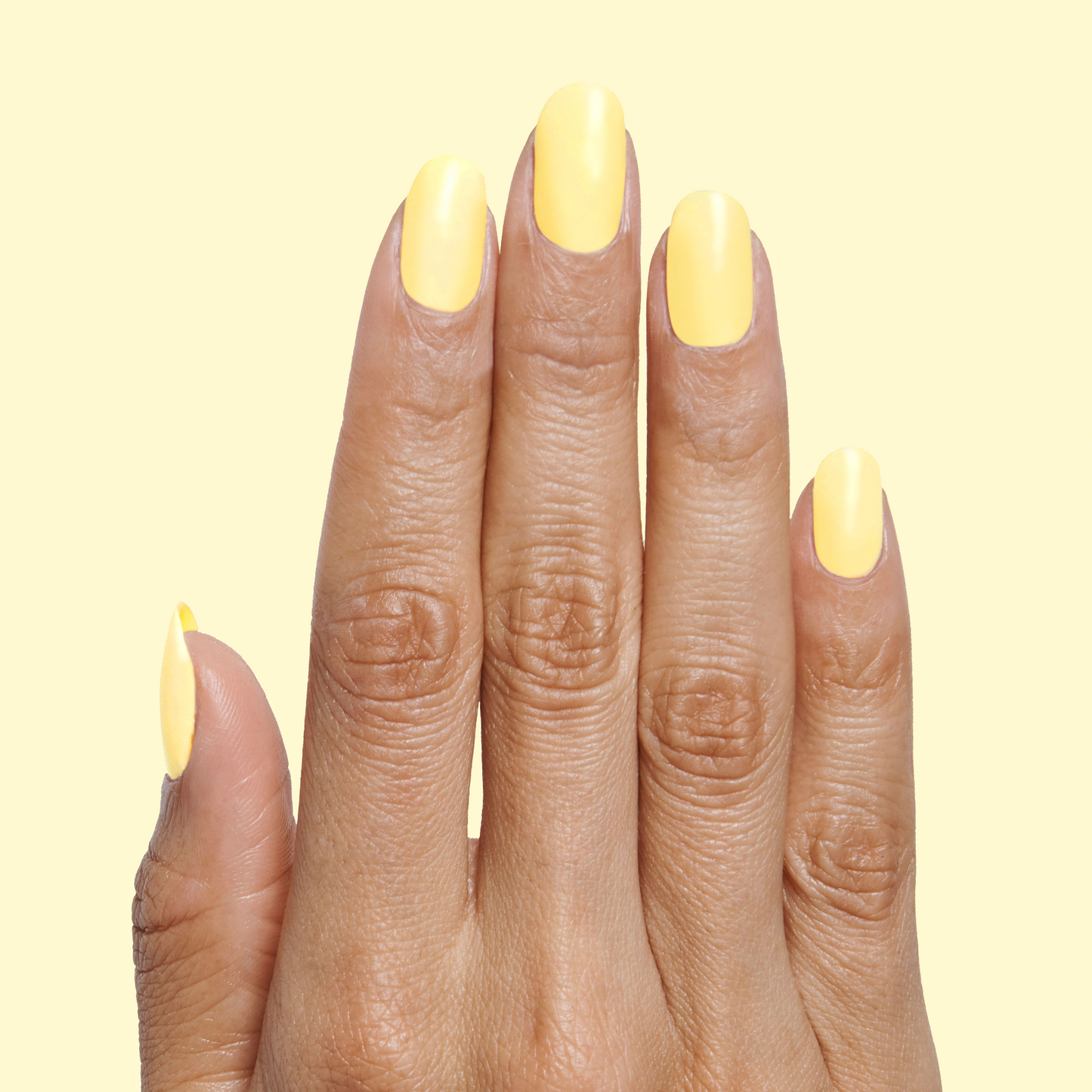 Hand with nails painted in Bright & Focused yellow for a bright, creative at-home manicure look using gel polish