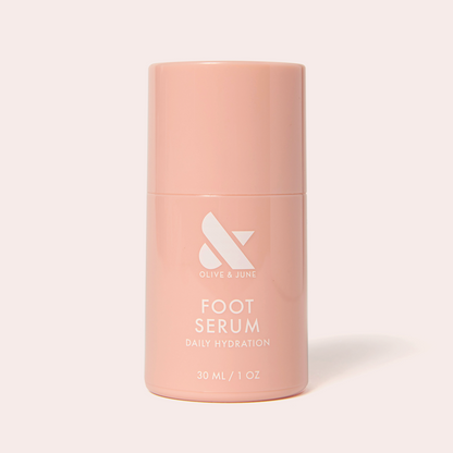 Soft pink bottle of Olive and June Foot Serum for daily hydration shown against light background