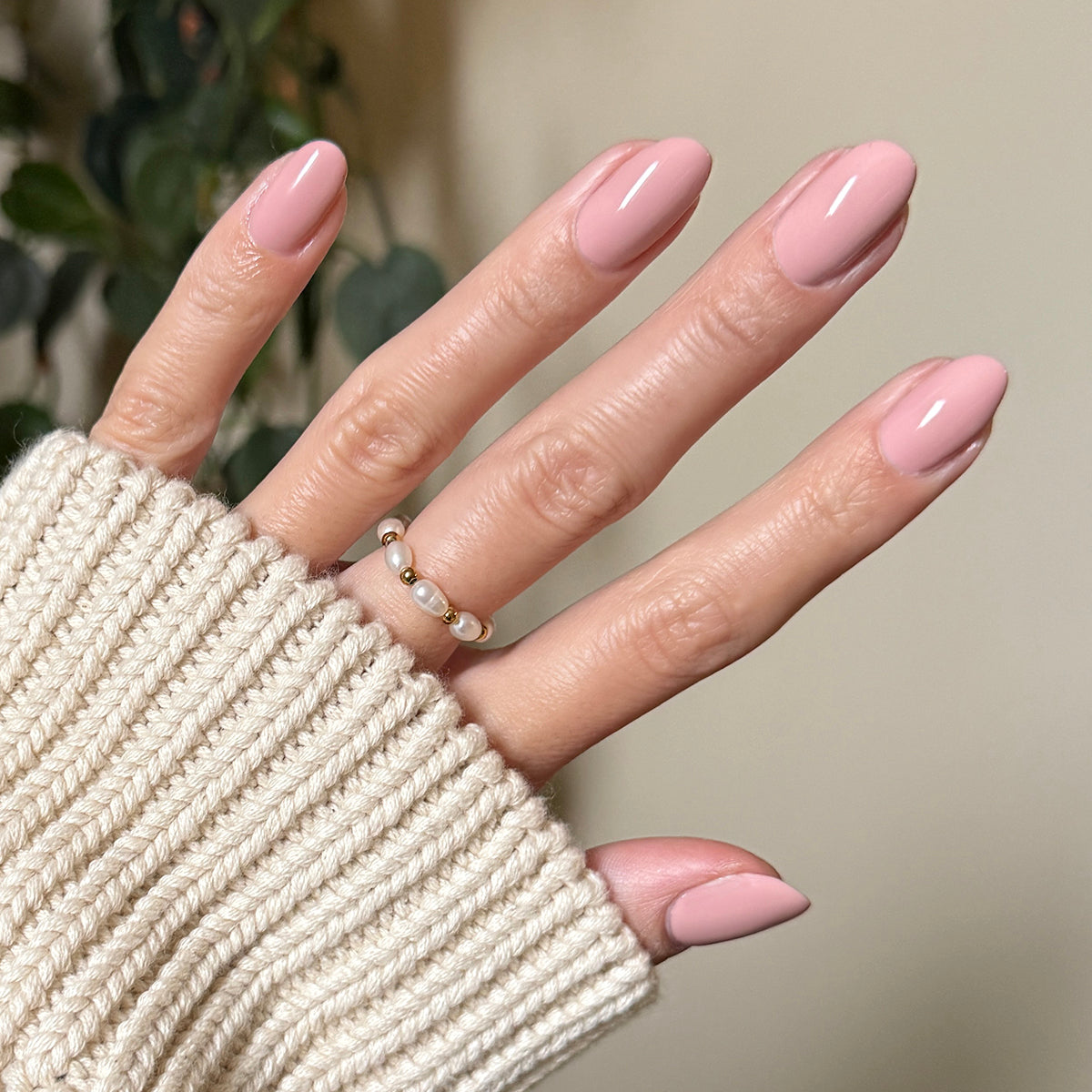 HZ - Gel manicure on almond-shaped nails in a soft rosy neutral shade with a cozy cream sweater background