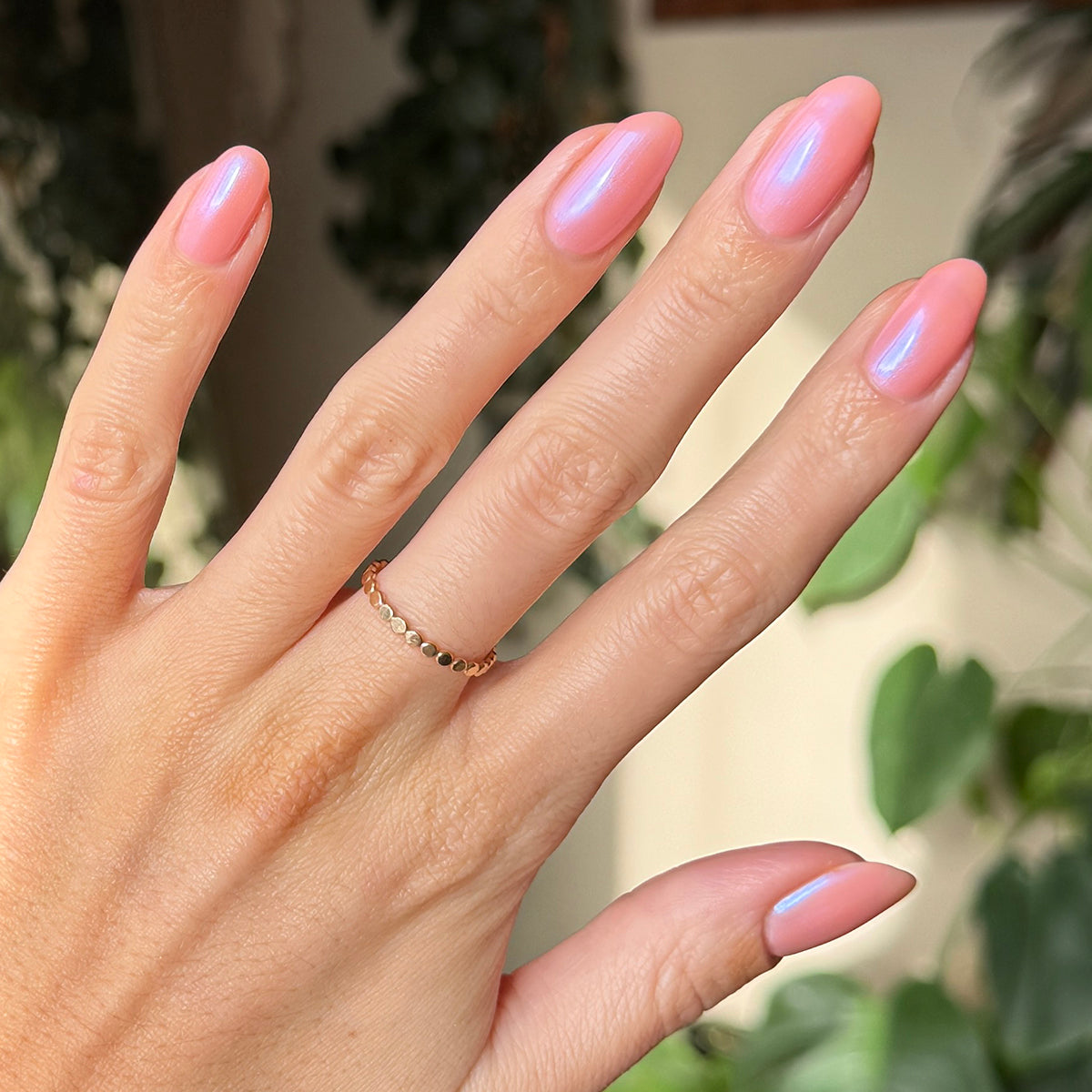 Hand with medium-length nails painted in sheer bubble gum pink-blue iridescent Olive Y'all gel polish manicure