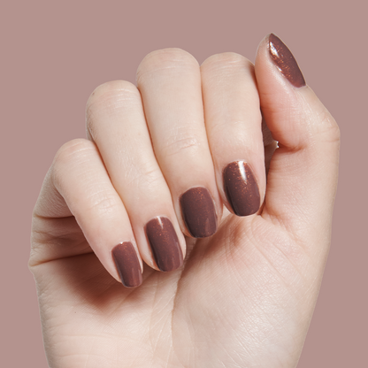 Hand with medium-length nails polished in Goal Getter - Gel, a shimmering chocolatey neutral gel manicure on pale skin