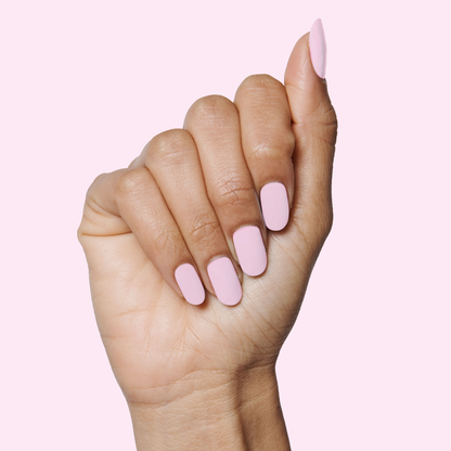 Hand with medium-length nails painted in glowy pastel pink polish Cockatoo on soft pink background