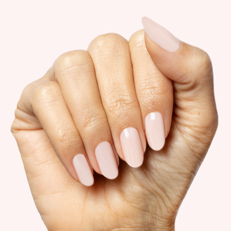 Hand with nails painted in sheer milky pink Puffball gel polish manicure on pale background